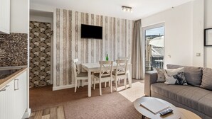 A modern living space with a dining area, a sofa, and a flat-screen TV mounted on the wall.