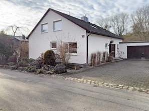 A two-story house with a paved driveway, a garage, and a well-maintained garden.