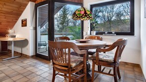 A dining area with a round table, wooden chairs, and a stained glass window.