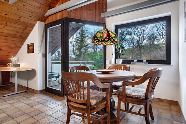 A dining area with a round table, wooden chairs, and a stained glass window.