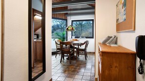 A dining area with a wooden table and chairs, a bulletin board, and a telephone.