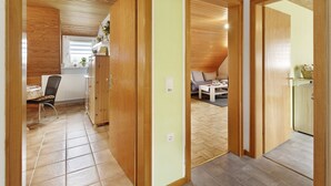 Une pièce avec un plafond en bois, un coin repas comprenant une table et des chaises, et une kitchenette équipée de placards.