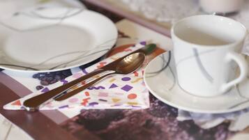 Ein Tisch mit einem weißen Teller, einer weißen Tasse und einem Löffel auf einer Serviette mit farbigem geometrischen Muster.