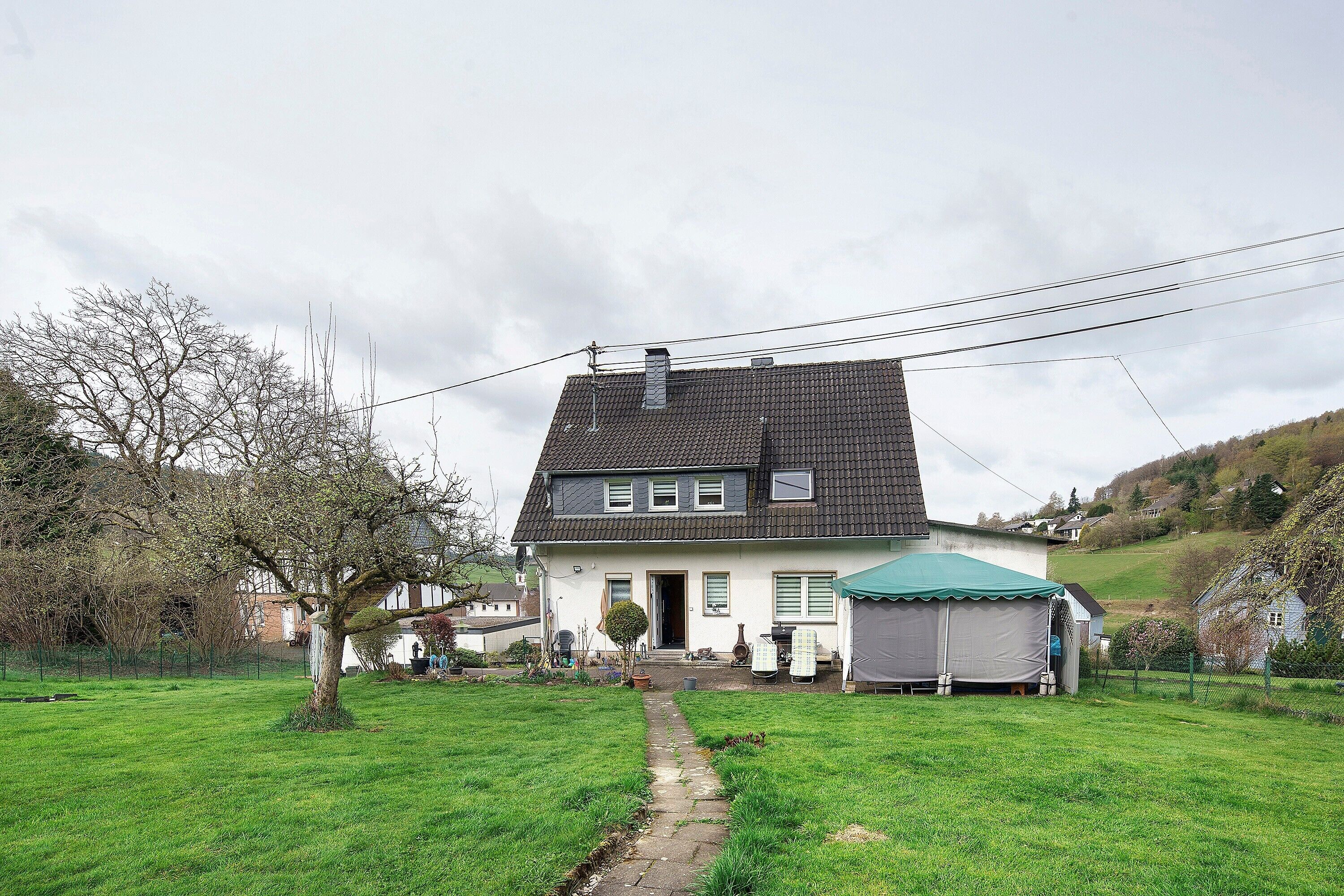 Ein Haus mit schrägem Dach, einer Haustür und einem kleinen Vorgarten.