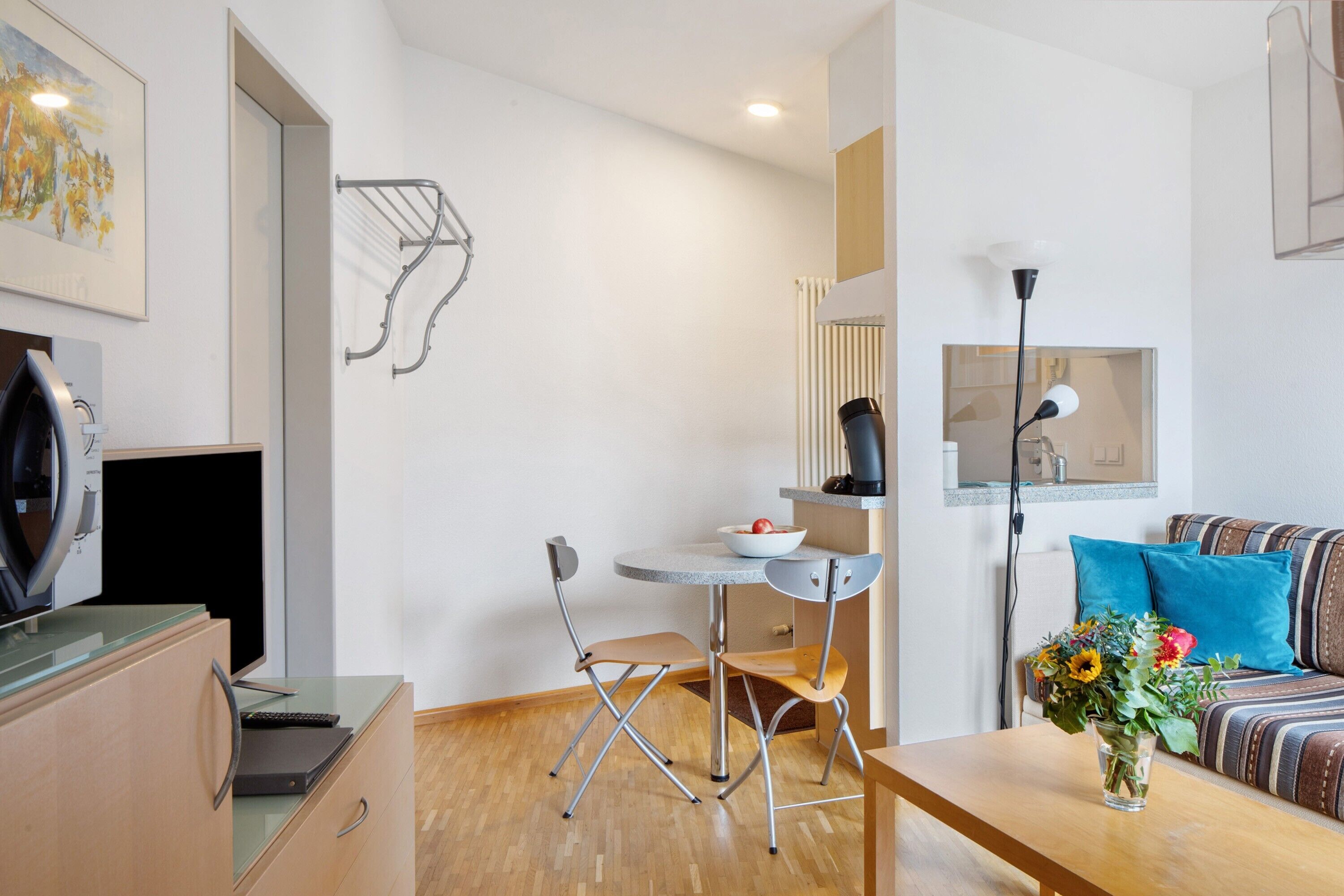 Een moderne woonkamer met een bank, een salontafel, een eettafel met stoelen, een televisie en een wandrek voor wasgoed.