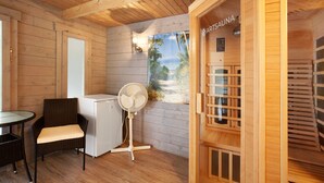 A sauna room with wooden walls, a fan, a chair, and a glass table. - Apartment 'Standfuss' with Private Terrace, Garden, and Wi-Fi (Dausenau)