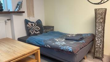 Une chambre à coucher comprenant un lit, une table en bois, une décoration murale en macramé et un élément décoratif mural.