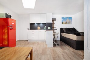 A compact living space with a kitchenette, a dining area, and a bed.