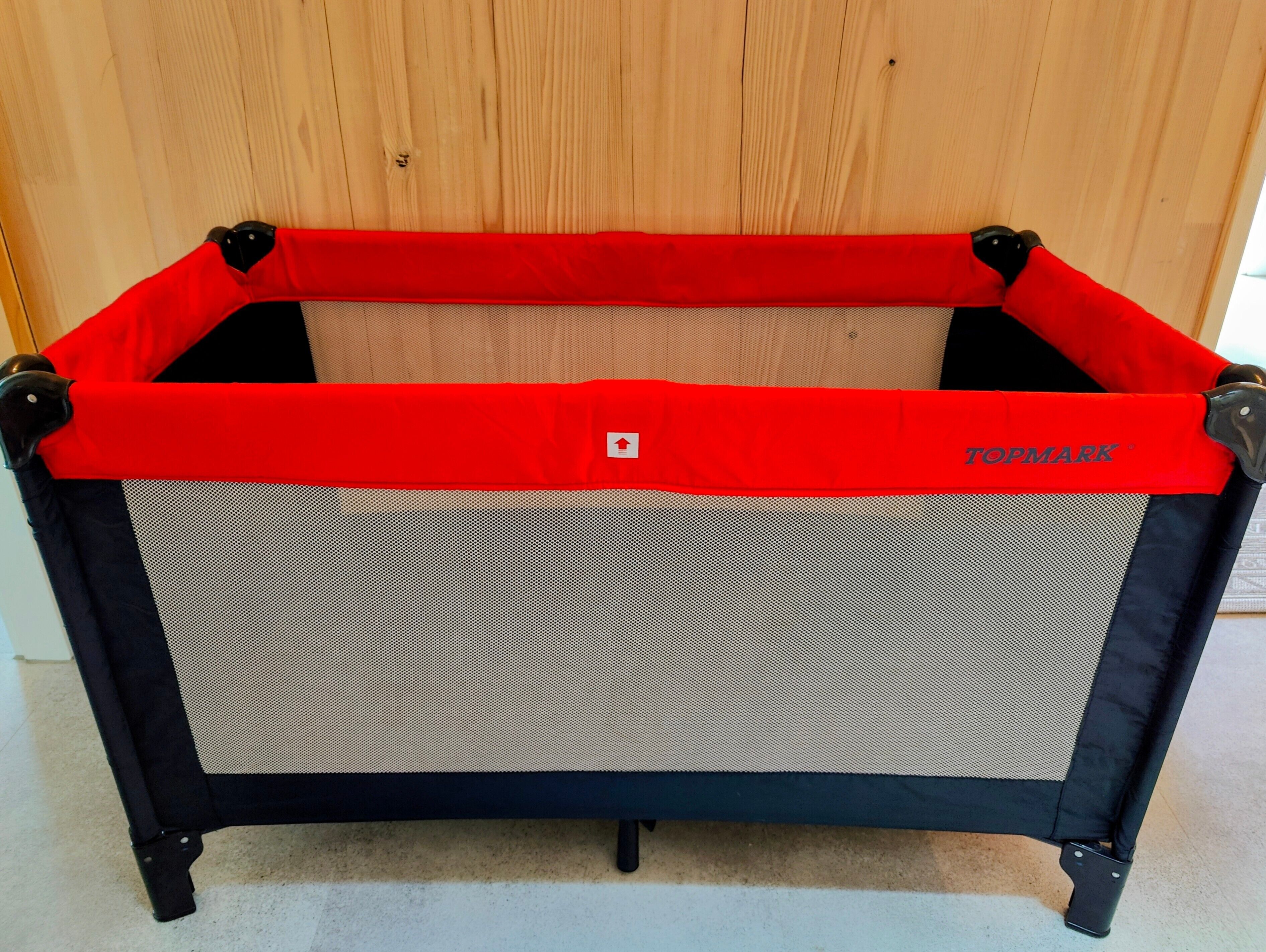 A red and black baby playpen with a mesh top and a 'TOPMARK' label.