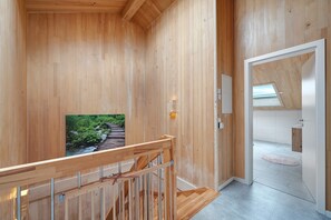 A wooden interior with a staircase, a framed picture, and a view into an adjacent room.