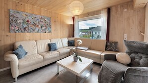 Una sala de estar moderna con un sofá color beige, una mesa de centro blanca y un sillón gris.