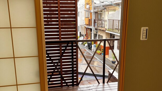 Une porte coulissante traditionnelle japonaise donnant sur un balcon avec vue sur un quartier résidentiel.