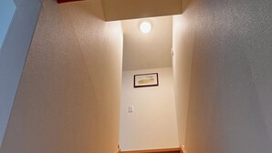 Un escalier en bois, avec un luminaire au sommet et un tableau encadré accroché au mur.