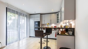 Eine moderne Küche mit Barhocker, Essbereich und großem Fenster.