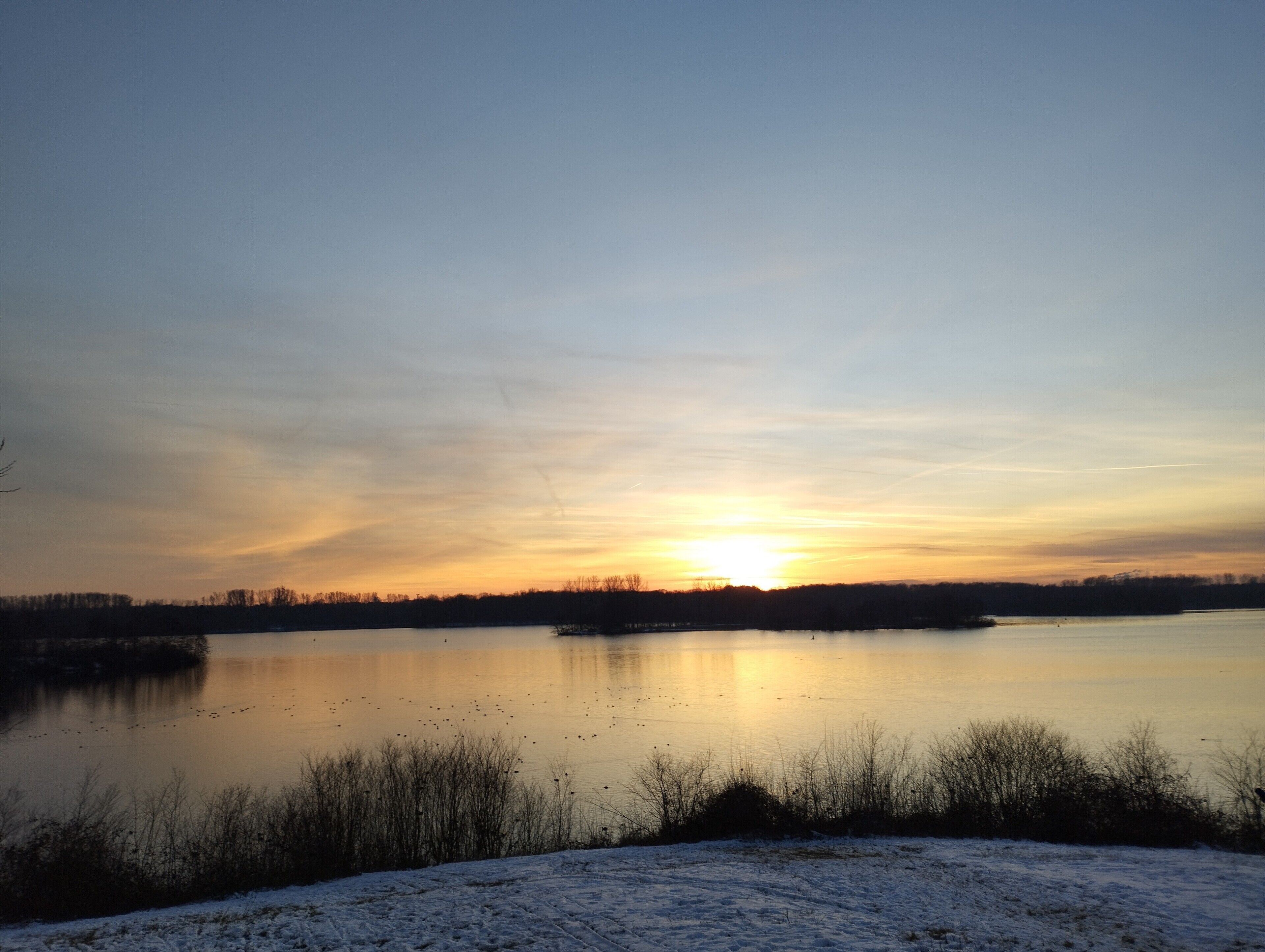 A calm lake at sunset with a clear sky.
