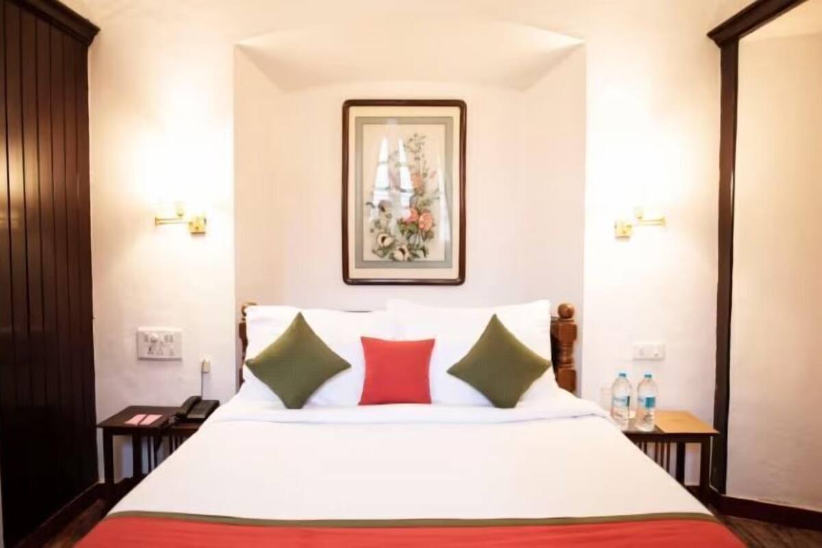 A hotel room with a large bed, a framed floral artwork on the wall, and two bedside lamps.