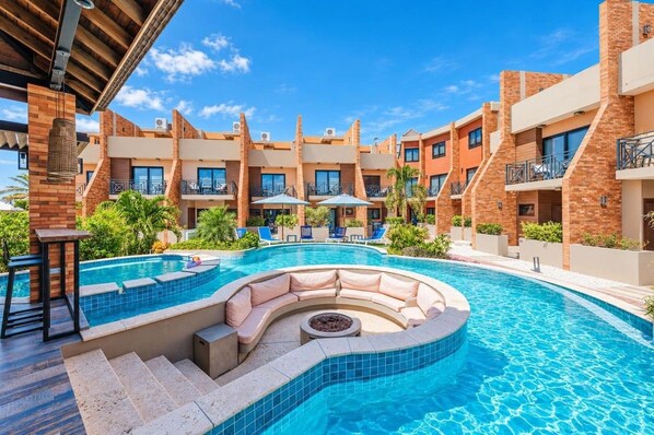 A hotel with a swimming pool, outdoor seating, and multiple balconies.