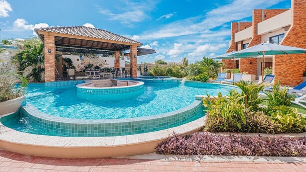 A swimming pool with a sun terrace, lounge chairs, and a covered seating area. - LUX 3BR House Pool Gym 7-Min Walk to Palm Beach - Porta al Sole 19 by Bocobay (Noord)
