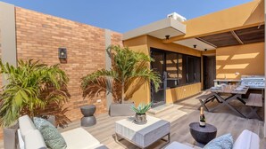 An outdoor patio area with seating, a barbecue grill, and potted plants. - LUX 3BR House Pool Gym 7-Min Walk to Palm Beach - Porta al Sole 19 by Bocobay (Noord)