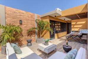 An outdoor patio area with seating, a barbecue grill, and potted plants. - LUX 3BR House Pool Gym 7-Min Walk to Palm Beach - Porta al Sole 19 by Bocobay (Noord)