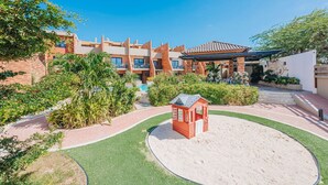 A hotel with a pool, a small red playhouse, and a well-maintained garden. - LUX 3BR House Pool Gym 7-Min Walk to Palm Beach - Porta al Sole 19 by Bocobay (Noord)