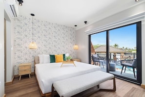 Ein modernes Schlafzimmer mit einem großen Bett, einer Bank, einem Nachttisch und Blick auf einen Pool und einen Außenbereich.