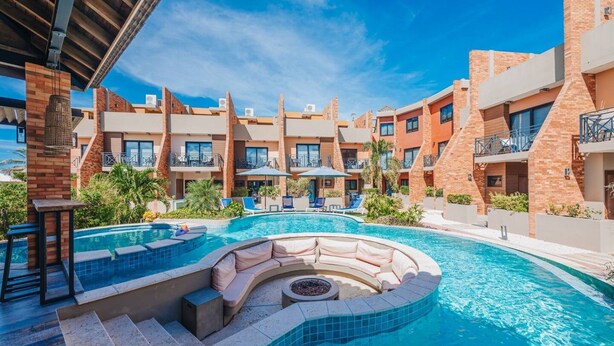 Un hôtel doté d’une piscine, de chaises longues et d’un espace salon abrité.