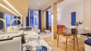 Ein modernes Hotelzimmer mit einem Marmoresszimmer, einem separaten Essbereich und einer Sitzecke mit rundem Tisch und Stühlen.