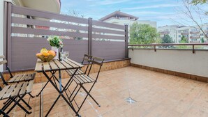 An outdoor patio with a table and chairs, a decorative bowl with fruits, and a view of surrounding buildings. - Lumina apartments with 2 terrace (Warsaw)