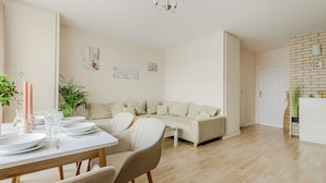 A modern living room with a sofa, dining table, and a white wall with artwork. - Lumina apartments with 2 terrace (Warsaw)