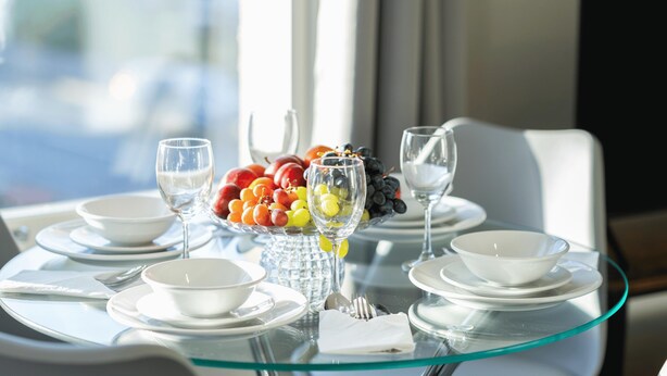 Een eettafel met een fruitschaal, wijnglazen en witte borden.