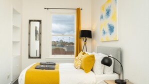 Een hotelkamer met een bed, een raam met gordijnen, een lamp en een schilderij aan de muur.