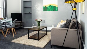 Een moderne woonkamer met een bank, salontafel en televisie.