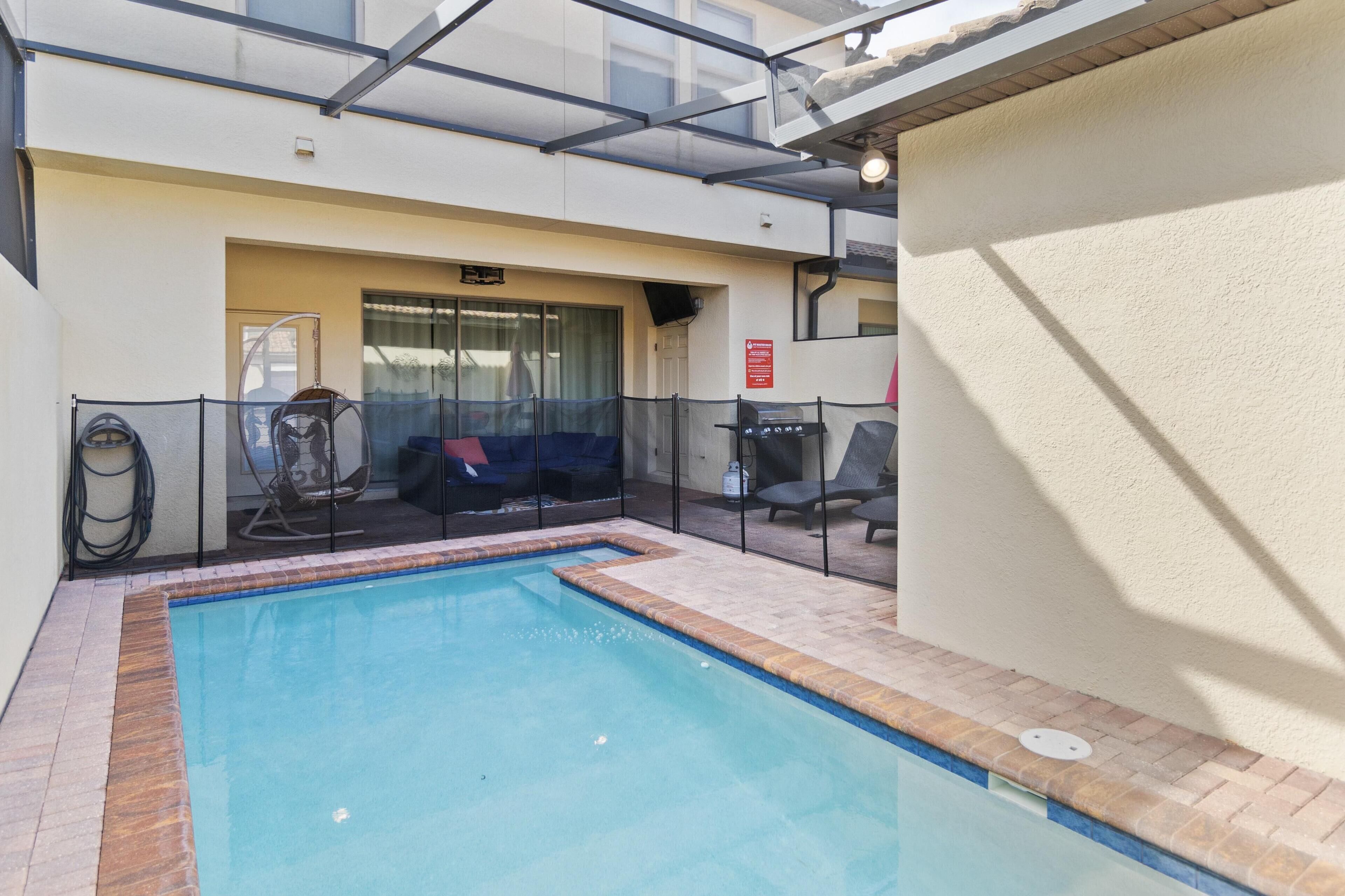 Una piscina con techo de cristal, una zona de estar cubierta y un cartel de extintor.