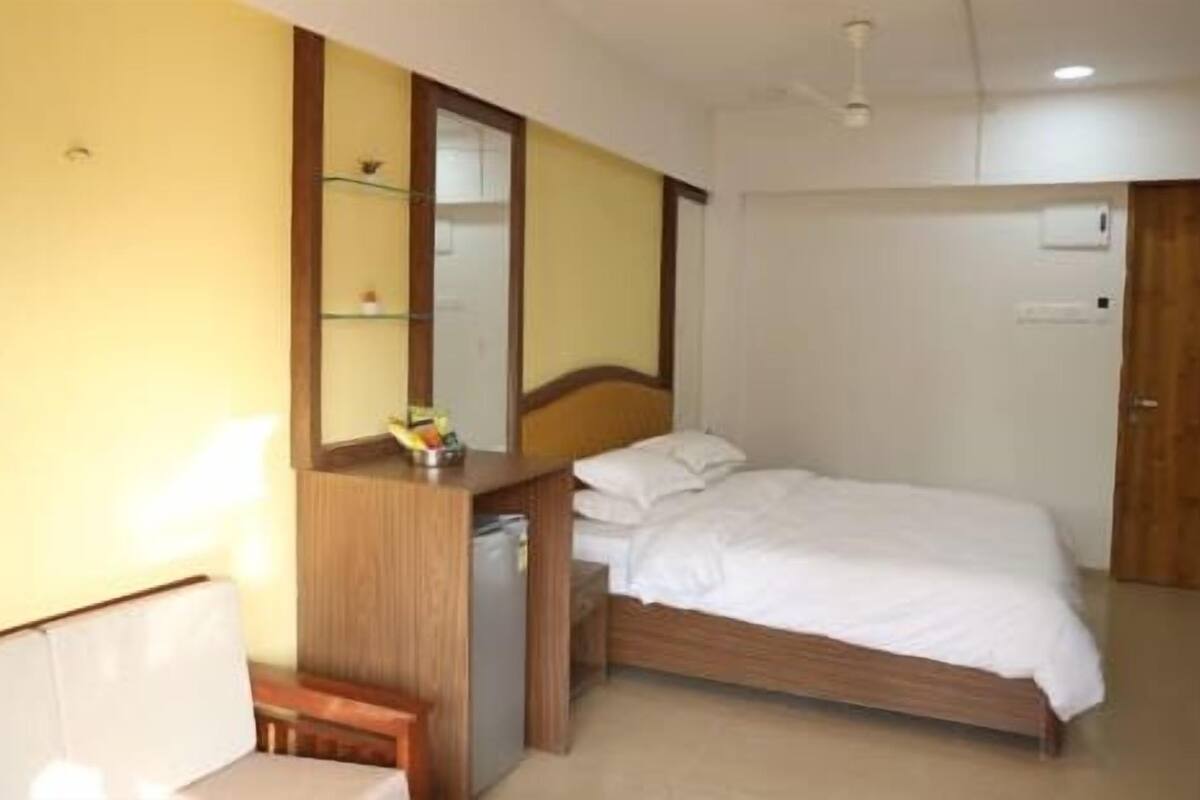 A bedroom with a bed, a bedside table, a mirror, and a wardrobe.