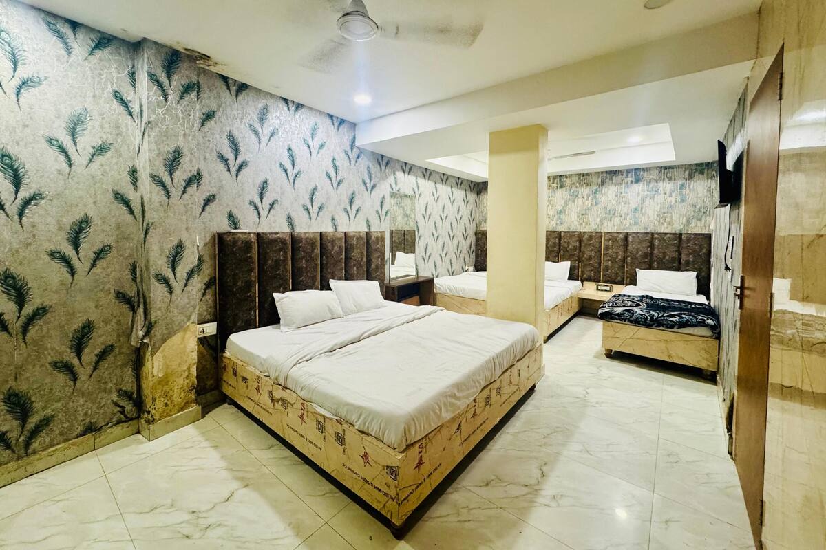 A hotel room with a large bed, a smaller bed, a TV, and a ceiling fan.
