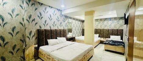 A hotel room with a large bed, a smaller bed, a TV, and a ceiling fan.
