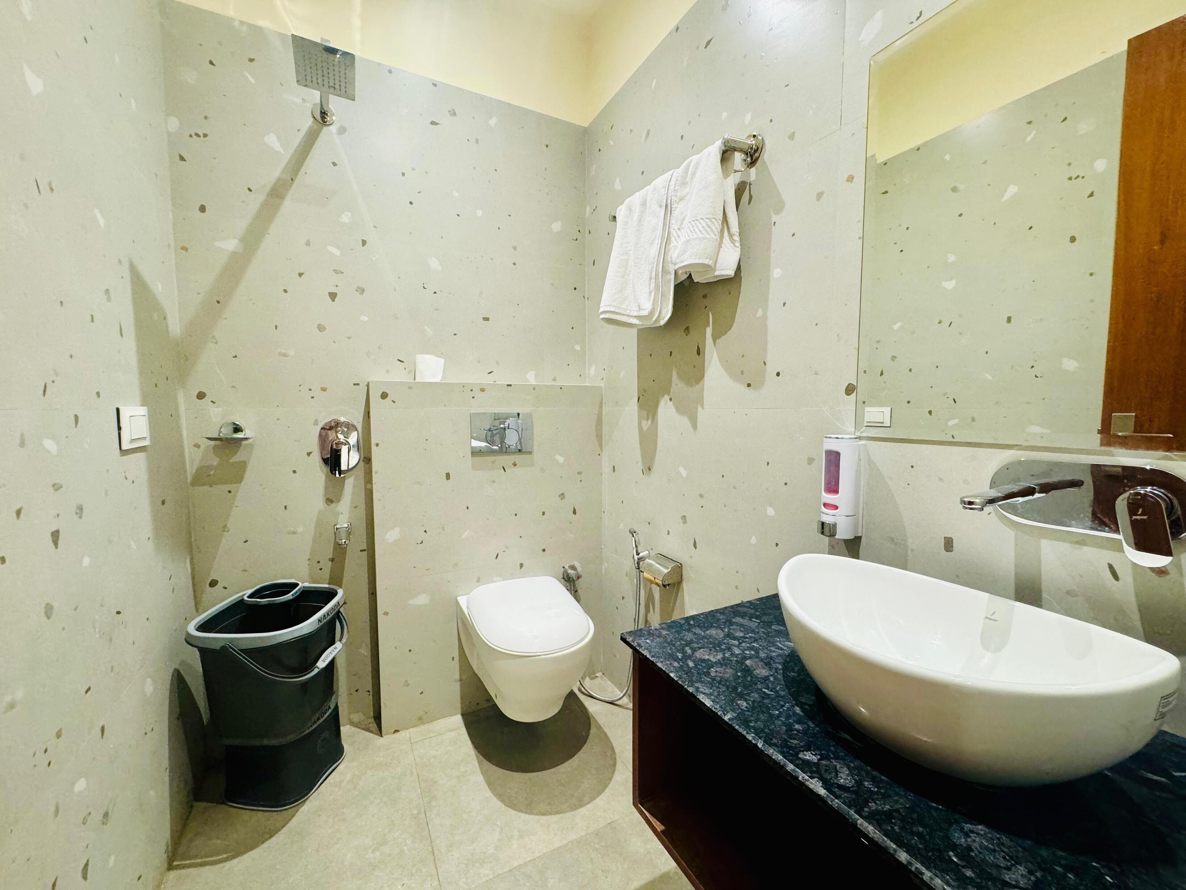 Un bagno moderno con un water sospeso, un lavandino ampio, uno specchio e una doccia.