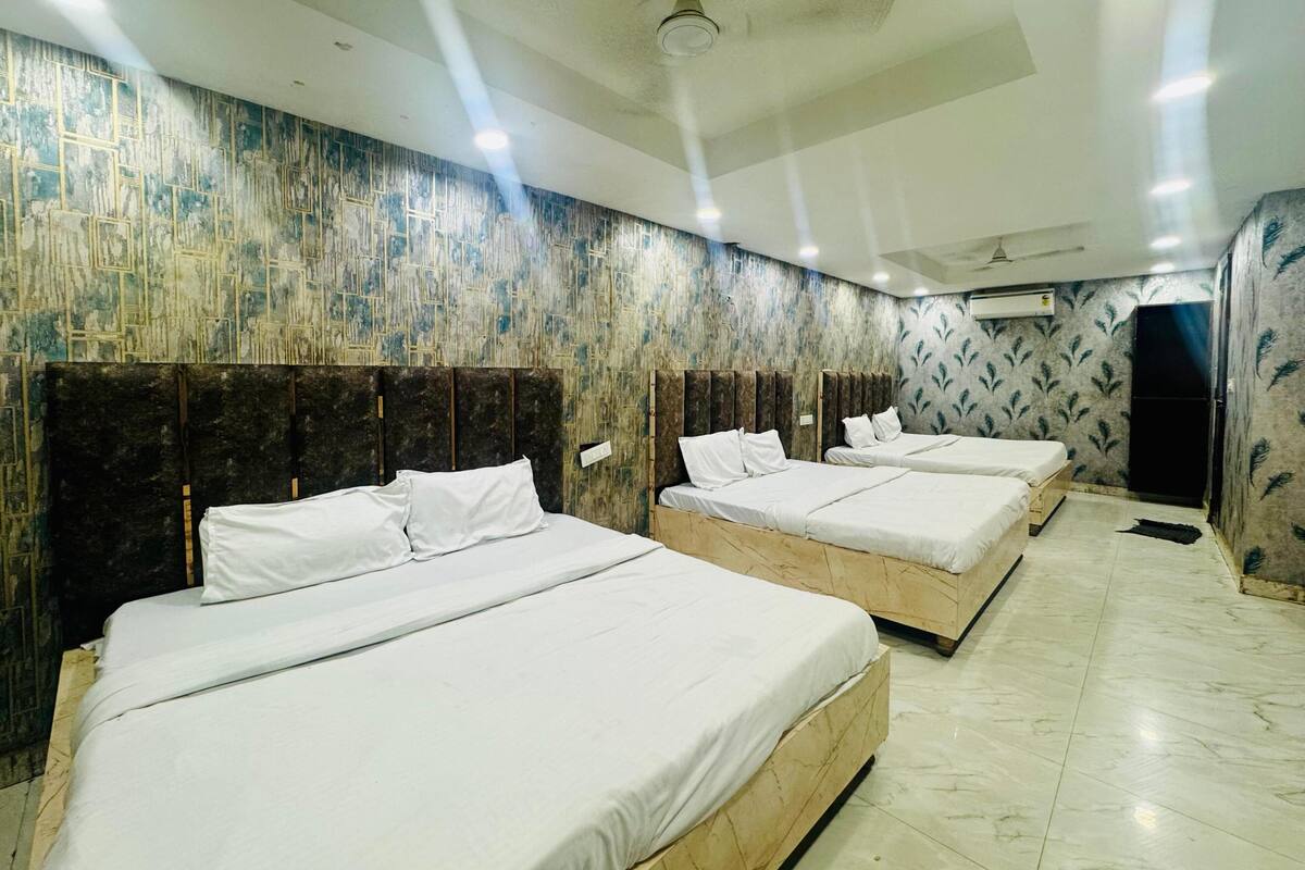 A hotel room with four beds, a ceiling fan, and patterned wallpaper.