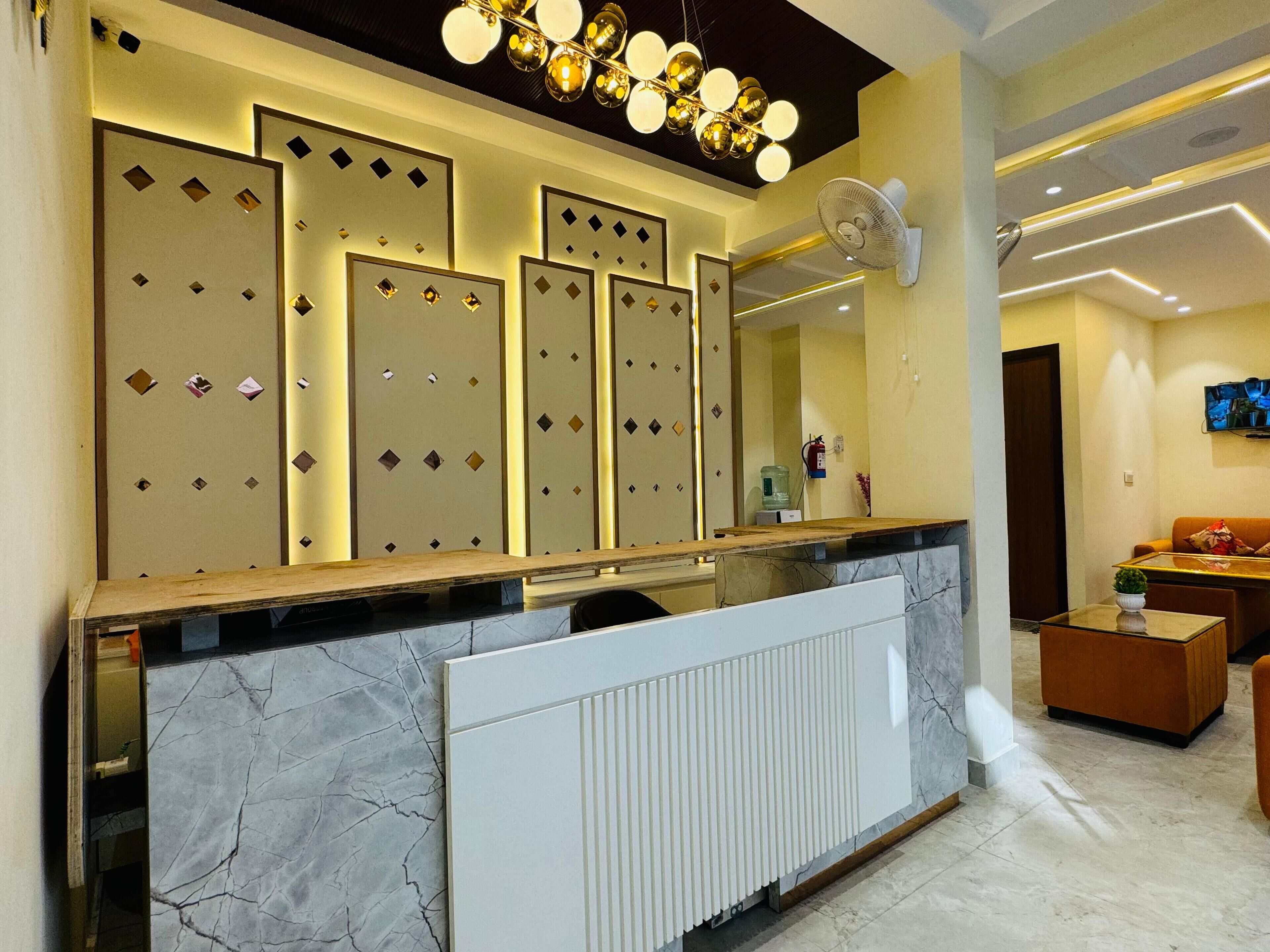 A reception area with a marble counter, a large mirror, and a modern ceiling light fixture.