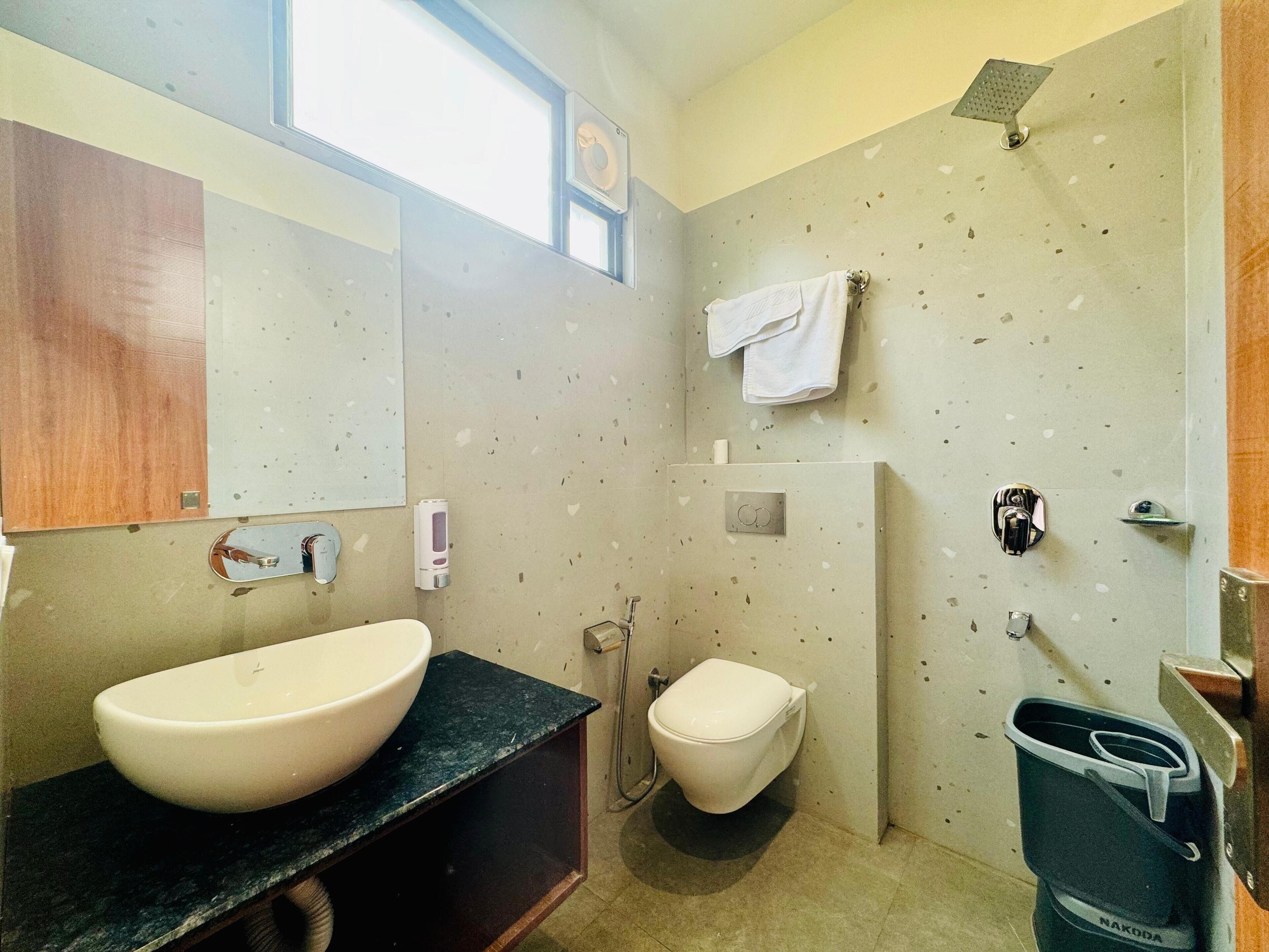 A bathroom with a large sink, toilet, and shower.
