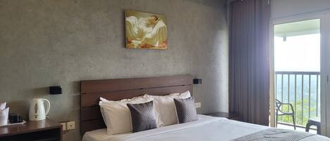 Ein Hotelzimmer mit einem großen Bett, einem Bild an der Wand, einer Kaffeemaschine und Blick ins Freie.