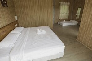 A hotel room with a large bed, a bedside table, and a small seating area. - Rich Villa Resort Semporna (Semporna)