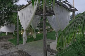 A covered outdoor seating area with draped fabric, a concrete pathway, and greenery. - Rich Villa Resort Semporna (Semporna)
