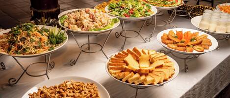 A buffet table with various dishes including salads, sandwiches, and snacks.