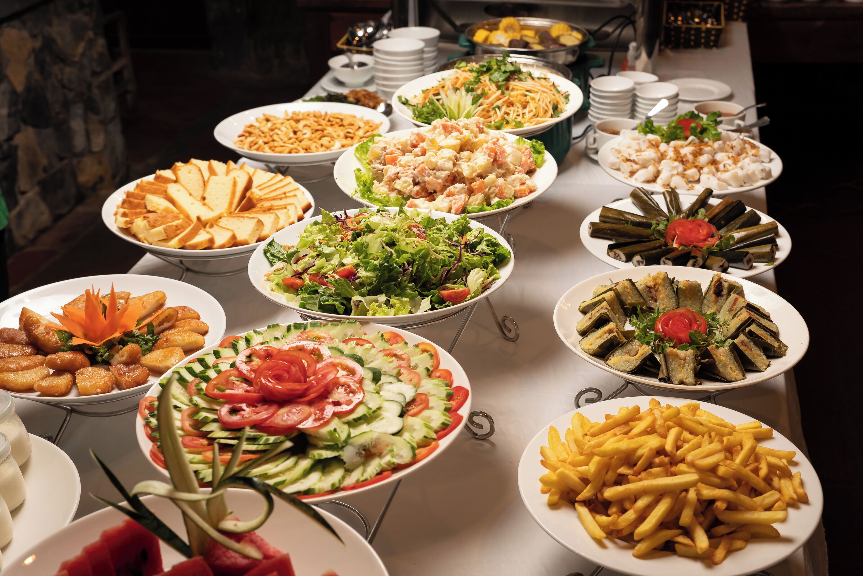 En buffet med flere retter, herunder salater, sandwiches og pommes frites.