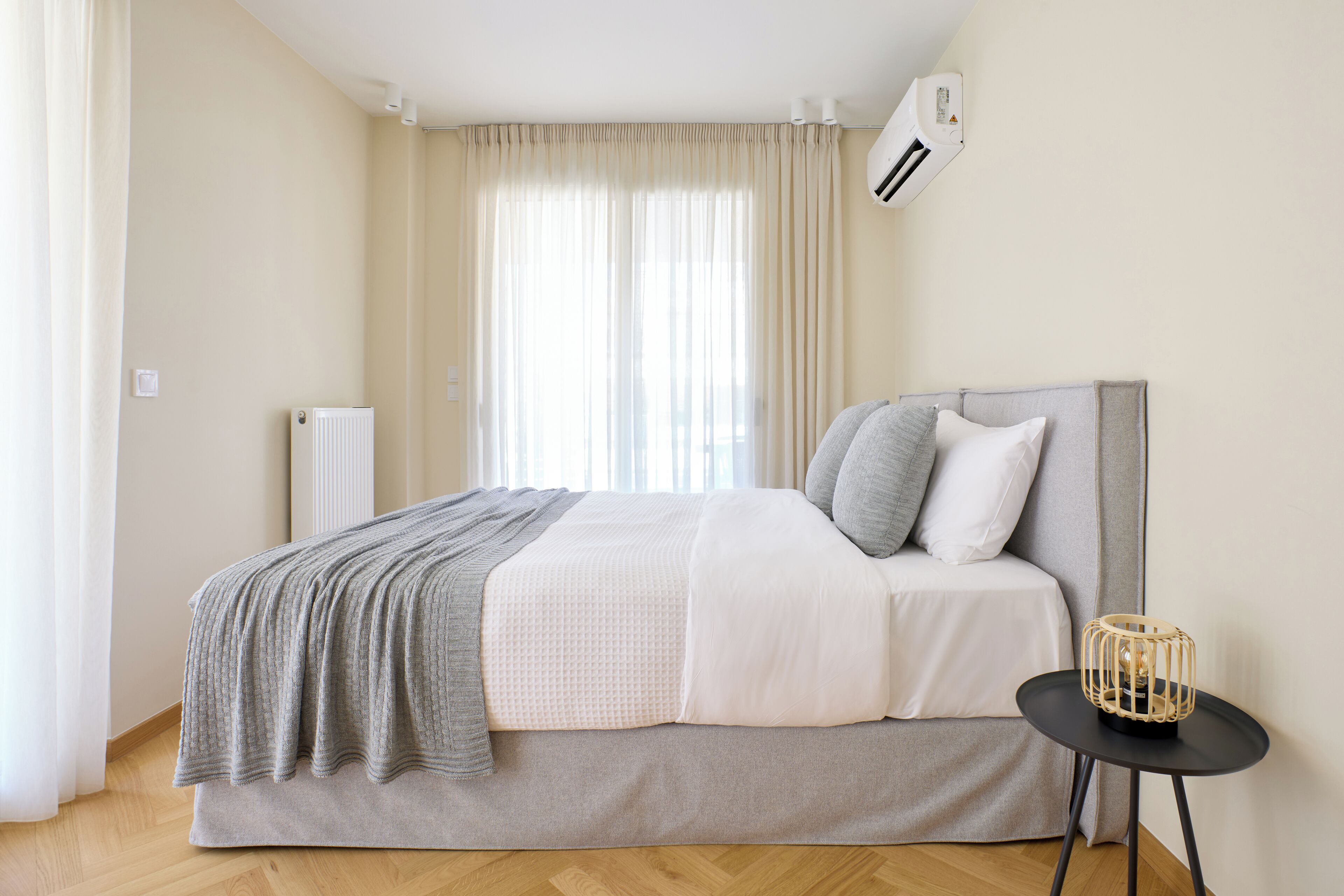 Une chambre à coucher moderne avec un lit, une table de chevet et une fenêtre avec des rideaux.