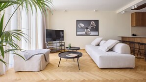 A modern living room with a sofa, a coffee table, and a TV. - The Samirah Luxury Residence C4 (Elliniko - Argiroupoli)