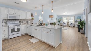 A spacious kitchen with white cabinetry, a central island, and pendant lighting.