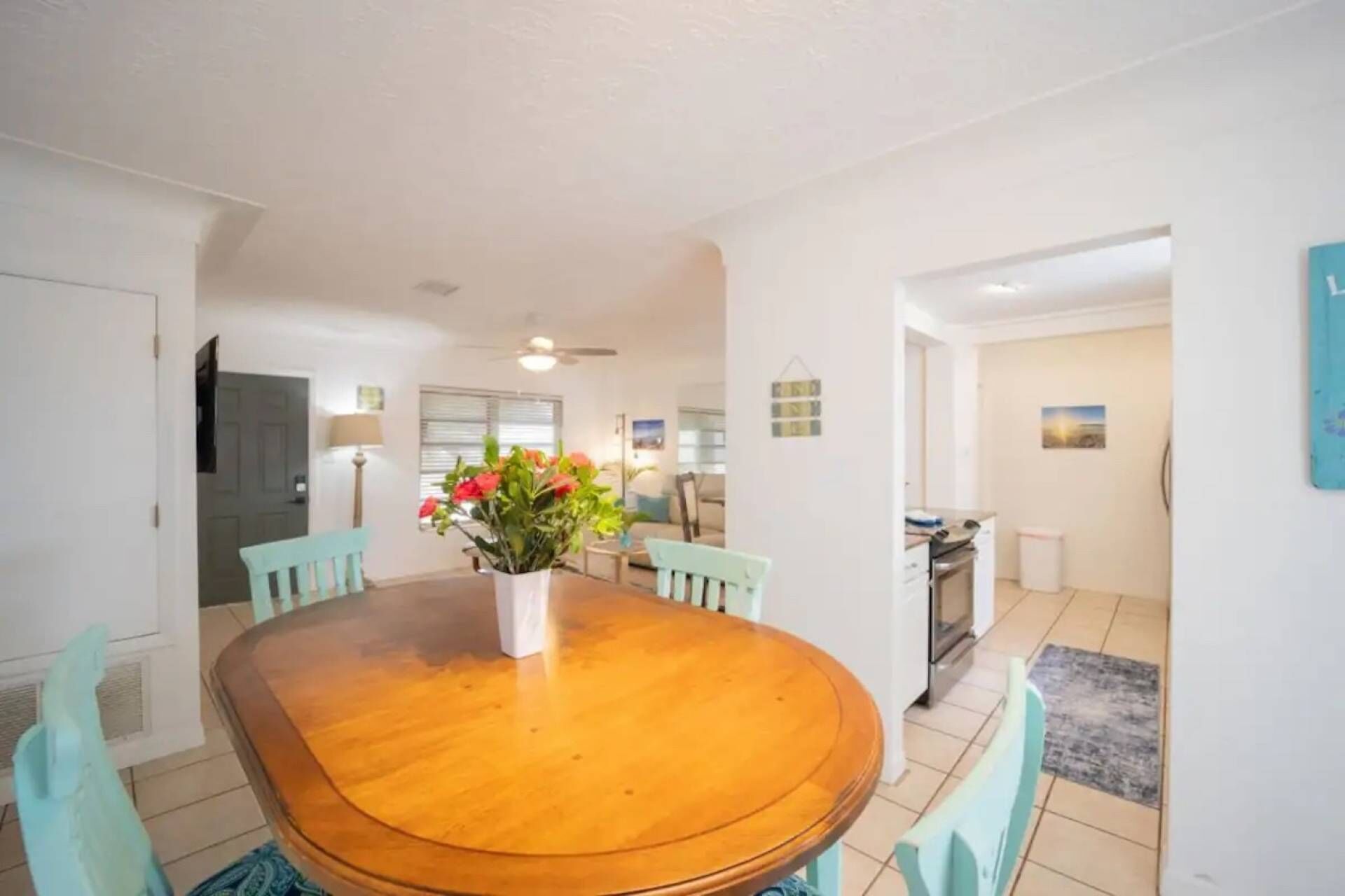 A dining area with a wooden table, four chairs, and a vase of flowers.